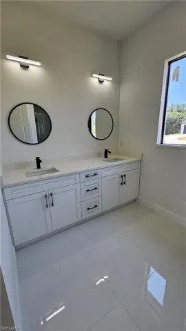 Full bath featuring double vanity and light tile patterned flooring