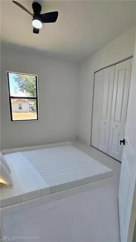 Tiled bedroom featuring ceiling fan and a closet