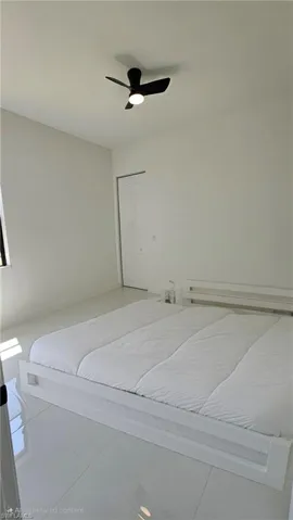 Tiled bedroom with a ceiling fan and a closet