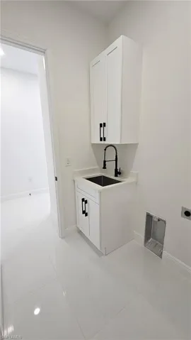 Laundry area featuring cabinet space, light tile patterned floors, and electric dryer hookup