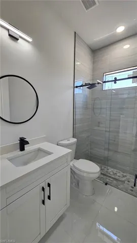 Bathroom with vanity, a shower stall, light marble finish floors, and recessed lighting