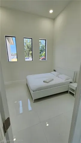 Bedroom with light tile patterned floors and recessed lighting