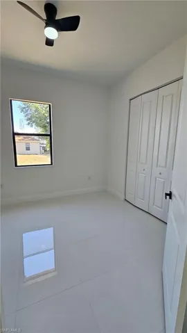Unfurnished bedroom with a ceiling fan, light tile patterned floors, and a closet