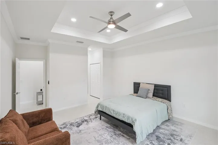 Bedroom featuring ornamental molding, a tray ceiling, recessed lighting, and a ceiling fan