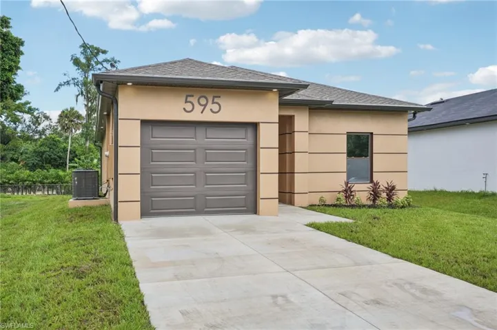 View of front of property featuring stucco siding, driveway, a front lawn, and a shingled roof