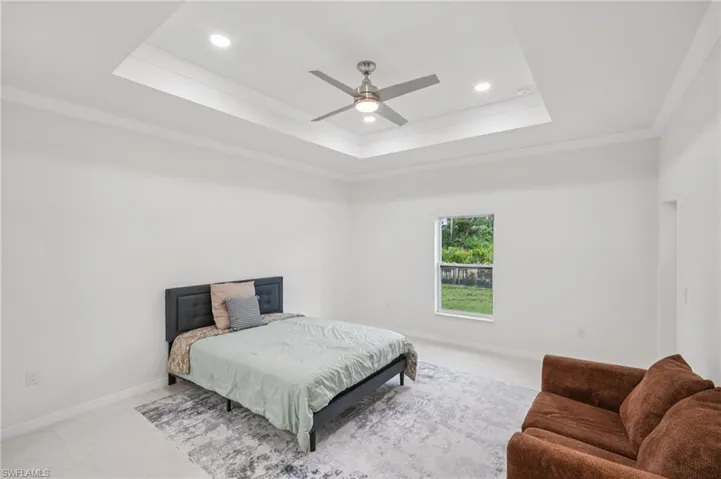 Bedroom featuring a tray ceiling, ornamental molding, ceiling fan, and recessed lighting
