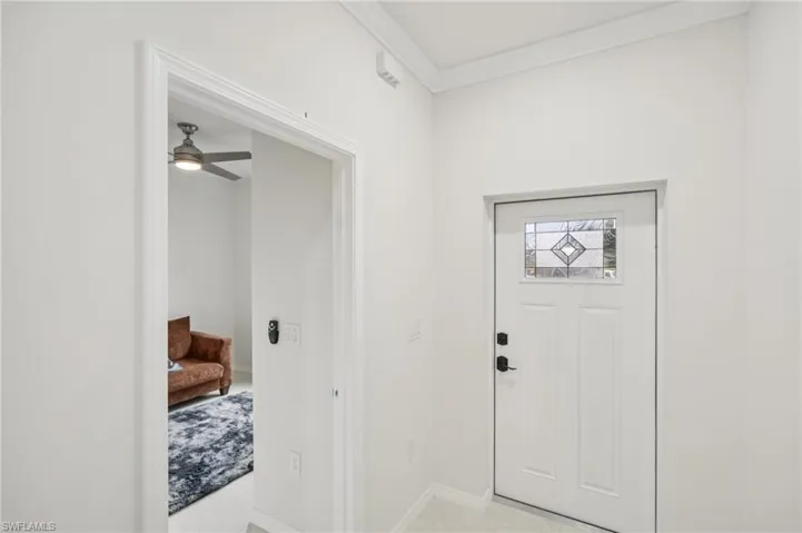 Foyer featuring ornamental molding, a ceiling fan, and light tile patterned flooring