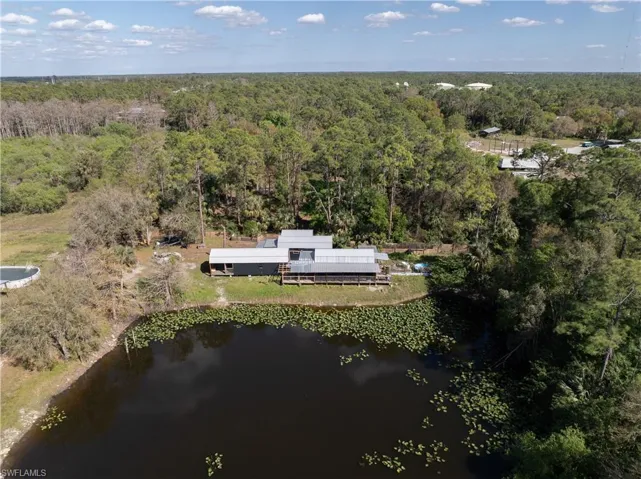 Birds eye view of property featuring a water view and a view of trees