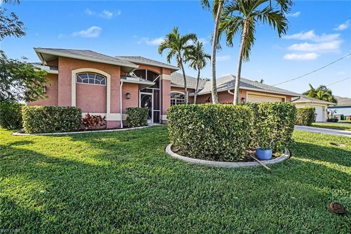Ranch-style home featuring a garage, a front yard, stucco siding, roof with shingles