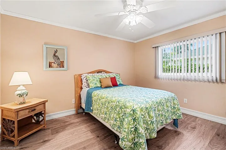 Bedroom featuring wood like finished floors, crown molding, and a ceiling fan