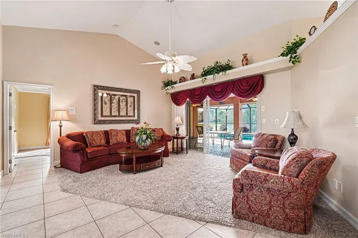 Living room with high vaulted ceiling, tile patterned floors, and ceiling fan