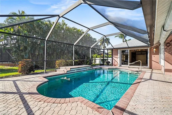 Outdoor pool, a patio area, screened enclosure, and a relaxing waterfall feature into pool