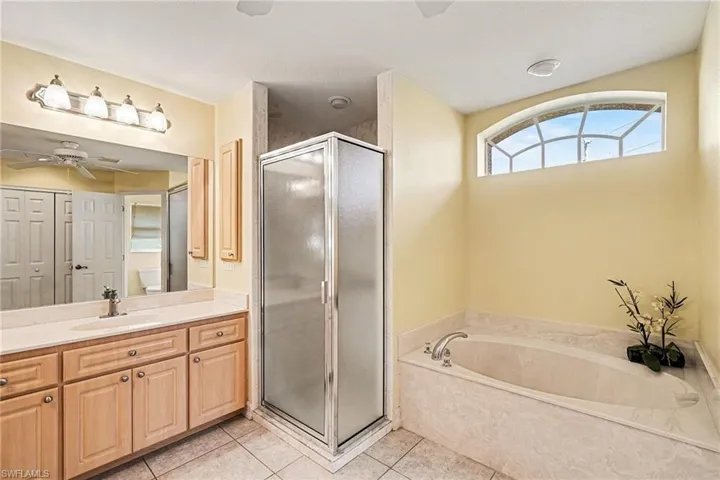 Bathroom with a stall shower, double vanity, a ceiling fan, light tile patterned floors, and a garden tub