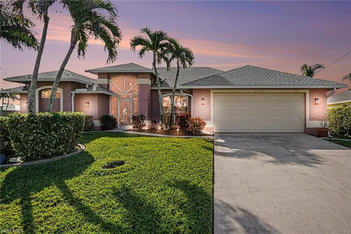 View of front of property with stucco siding, concrete driveway, a garage, and a lush lawn
