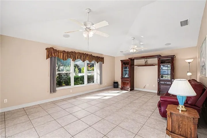 Family room with ceiling fan, light tile patterned floors, and high vaulted ceiling