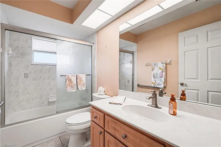 Bathroom featuring vanity, bath / shower combo with glass door, and light tile patterned floors