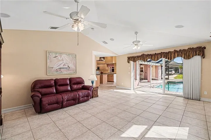 Family room with vaulted ceiling, light tile patterned floors, and ceiling fan