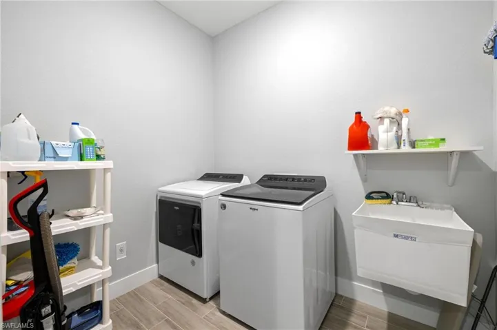 Laundry room with sink, washing machine and dryer, and light wood-type flooring