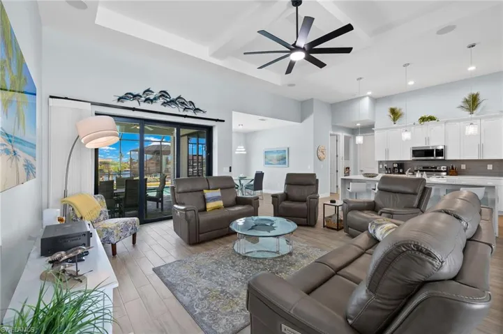Living room featuring beam coffered ceiling, light wood-like tile flooring, and ceiling fan