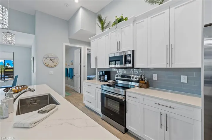 Kitchen with,Samsung stainless steel appliances, backsplash, white cabinets, and undermount sink