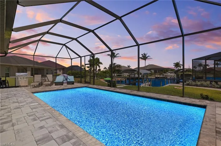 Pool at dusk with grilling area, screened enclosure pool area