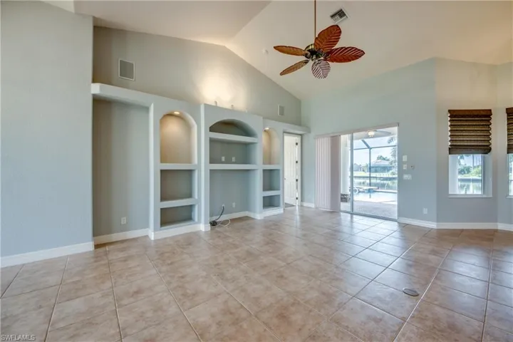 Unfurnished living room featuring light tile patterned flooring, high vaulted ceiling, and ceiling fan