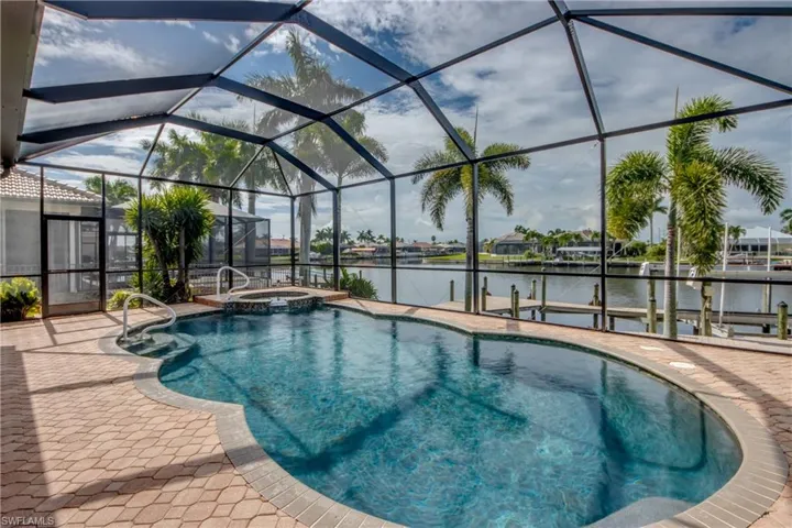 View of swimming pool with an in ground hot tub, a patio area, and glass enclosure