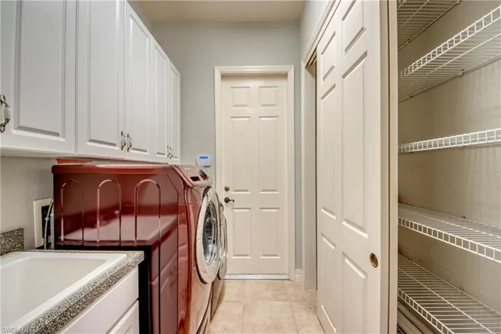 Laundry room featuring sink, washing machine and dryer, cabinets, and light tile patterned floors