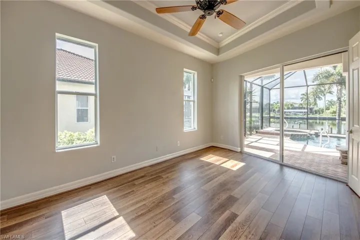 Spare room featuring ceiling fan, a tray ceiling, light hardwood / wood-style flooring, and ornamental molding