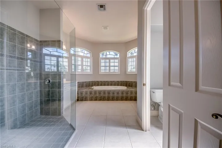 Bathroom with toilet, separate shower and tub, and tile patterned flooring