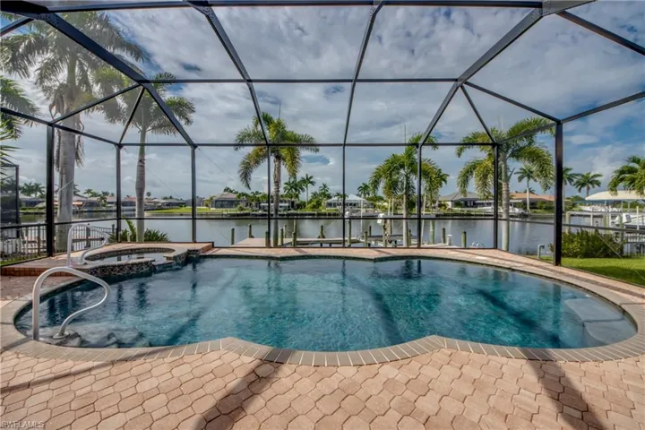 View of swimming pool with an in ground hot tub and glass enclosure