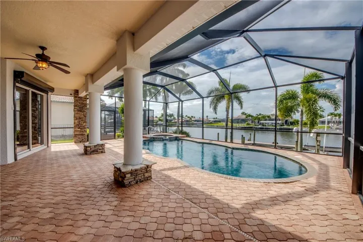 View of pool with a water view, a patio, ceiling fan, and a lanai