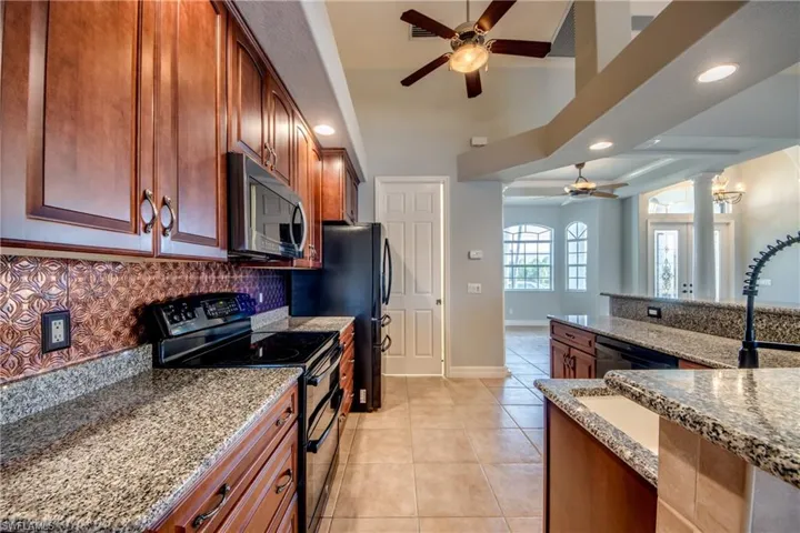 Kitchen featuring light tile patterned floors, light stone countertops, ceiling fan, and stainless steel appliances