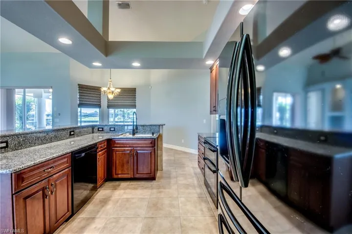 Kitchen featuring black appliances, a chandelier, sink, light stone countertops, and light tile patterned floors