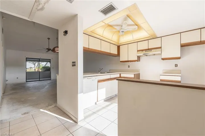 Kitchen featuring white cabinetry, white tile flooring, and a drop ceiling with integrated lighting