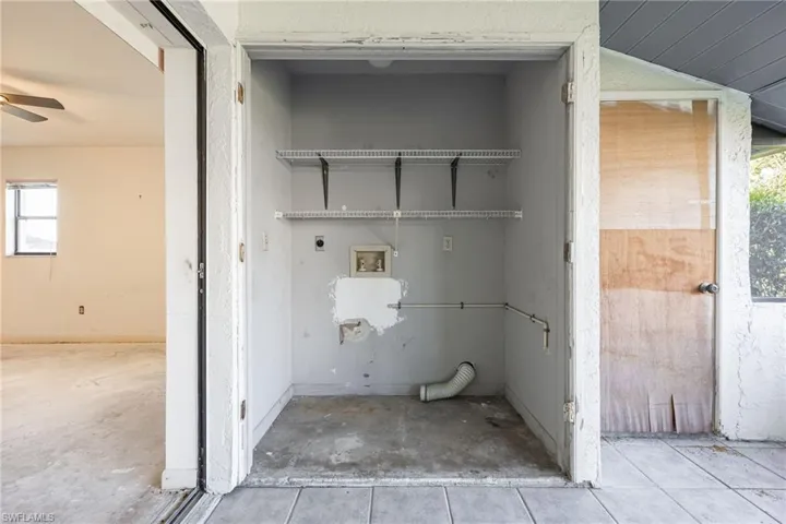 Utility closet featuring wire shelving, plumbing hookups, and a dryer vent