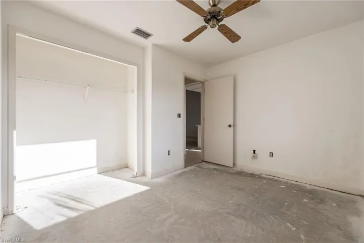 Room with neutral wall paint and a ceiling fan with wood-finish blades