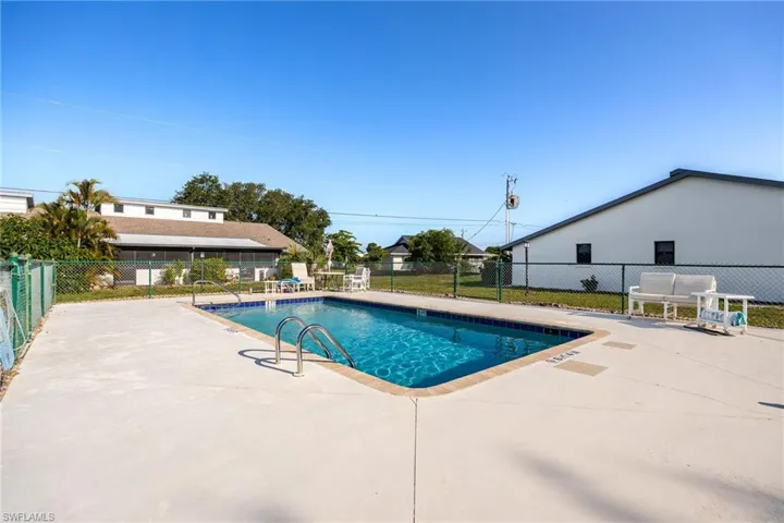 Rectangular swimming pool with blue tile border and integrated steps, surrounded by a light-toned concrete deck