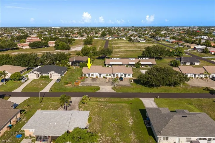 Aerial perspective showcasing a residential building with a light-colored shingle roof and a paved driveway