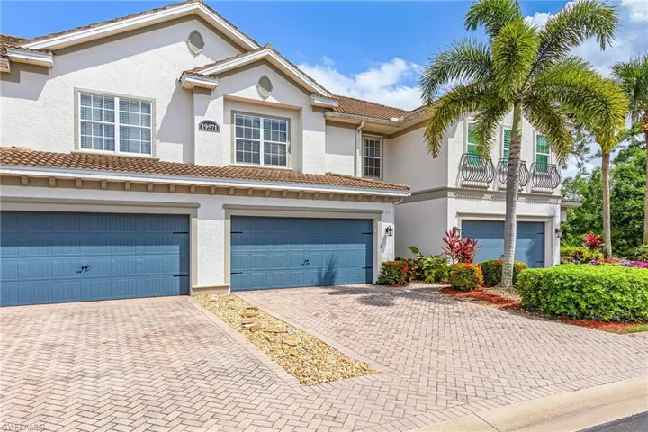 Exterior featuring white stucco, tile roofing, and multiple garages with blue paneled doors