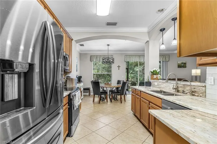Kitchen featuring stainless steel appliances, light wood cabinetry, natural stone countertops, and a subway tile backsplash