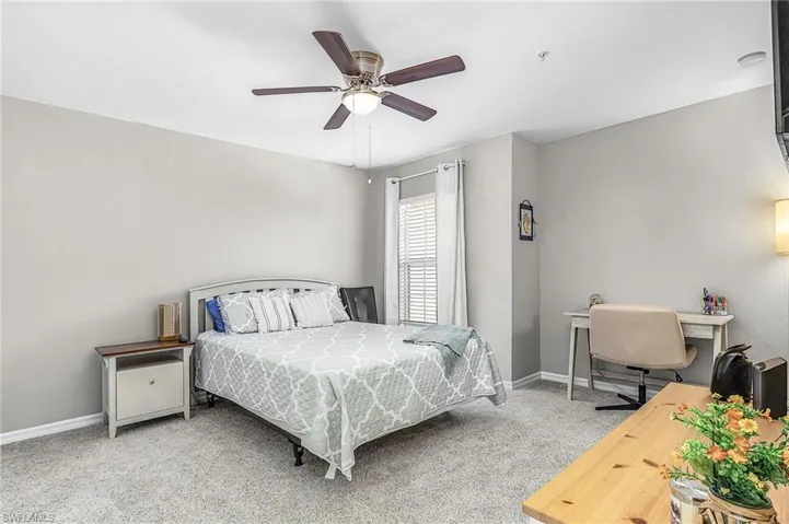 Carpeted room with a ceiling fan light fixture, light gray walls, white window blinds, and a built-in wall light