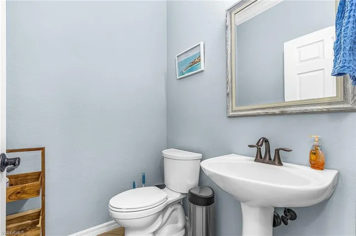 Pedestal sink with dark bronze hardware, a framed mirror, and a white two-piece toilet