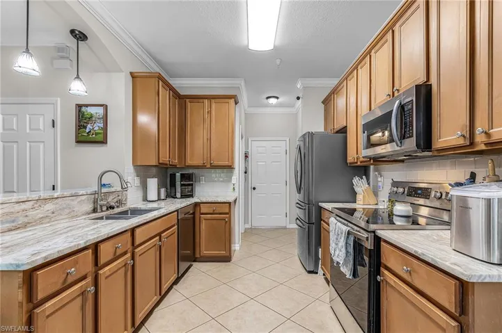 Kitchen featuring wood cabinetry, stainless steel appliances, and stone-look countertops