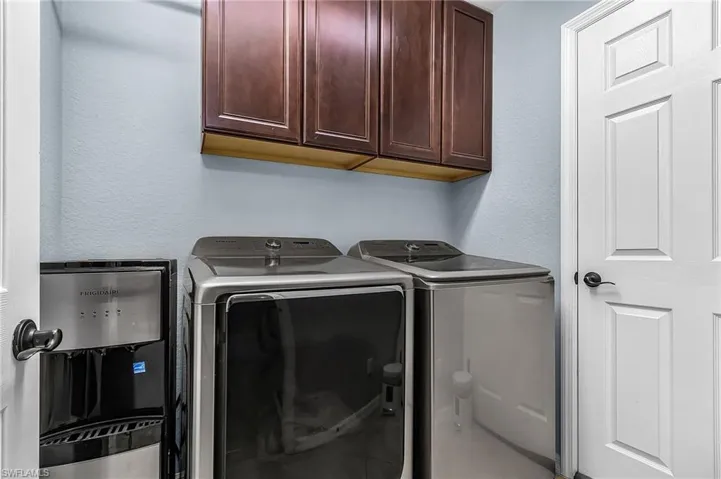 Laundry area featuring upper cabinetry, light blue walls, and a white panel door