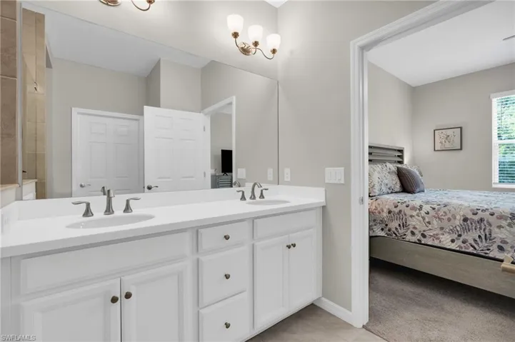 Full bathroom with double vanity, ensuite bath, a sink, and tile patterned floors