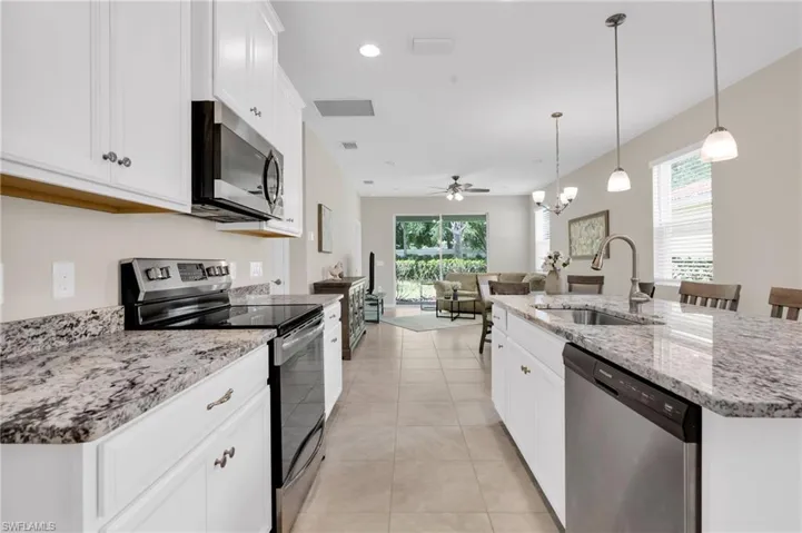 Kitchen featuring light tile patterned floors, a sink, visible vents, a kitchen island with sink, and appliances with stainless steel finishes