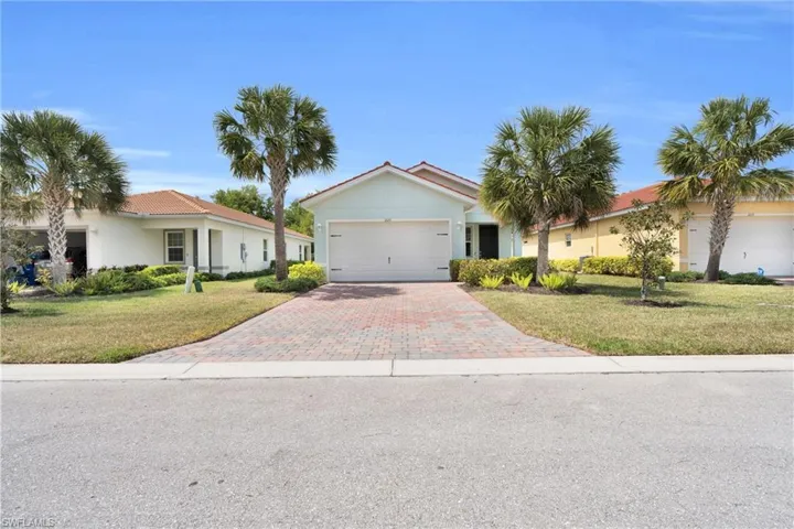 Ranch-style home with driveway, a garage, a front lawn, and stucco siding