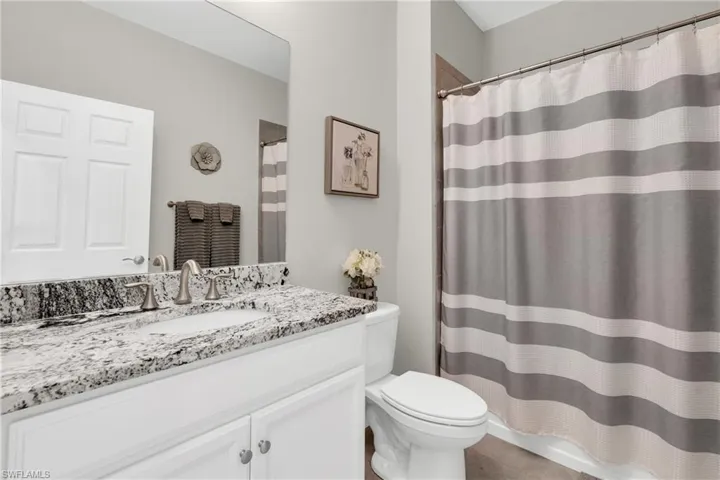 Full bathroom with toilet, vanity, and curtained shower