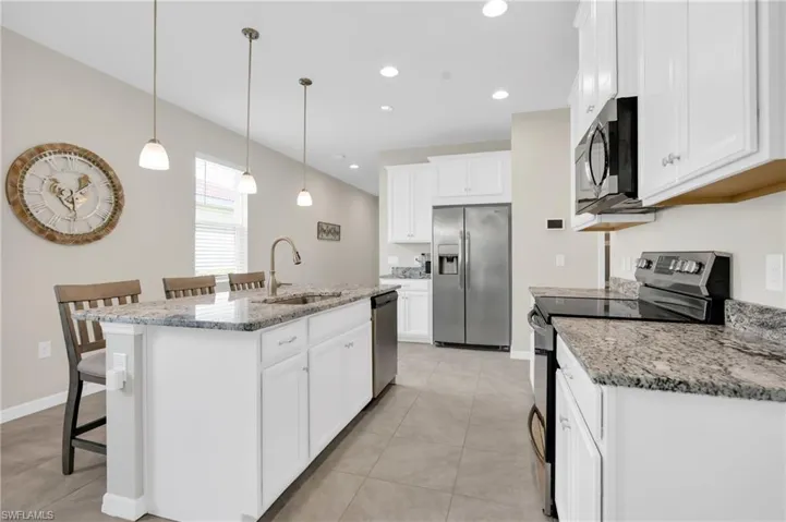 Kitchen featuring a sink, a kitchen bar, appliances with stainless steel finishes, a kitchen island with sink, and recessed lighting